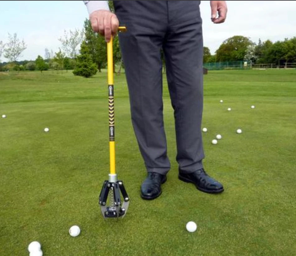 Greenkeeper holding the BMS Pitchmark Repair Tool on a green with golf balls around