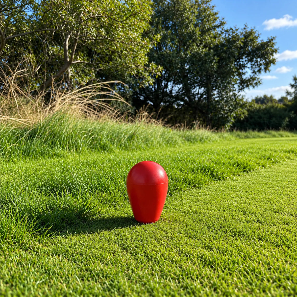Red pear shaped golf tee marker on a golf course tee