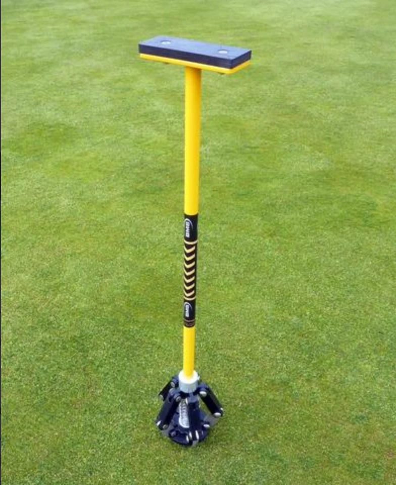 BMS Pitchmark Repair Tool with yellow shaft and handle standing on a golf green
