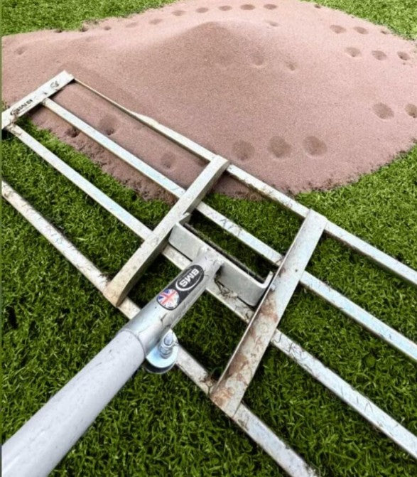 Level lute with a slatted aluminium head on turf beside a mound of sandy soil
