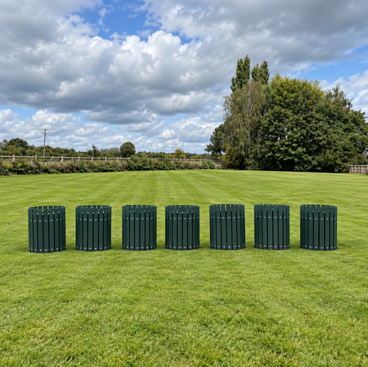 Seven Par Aide 20 gallon round trash containers in Hunter Green on a golf course lawn
