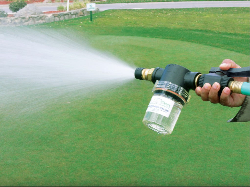 Greenkeeper spraying a golf green using a pellet applicator gun